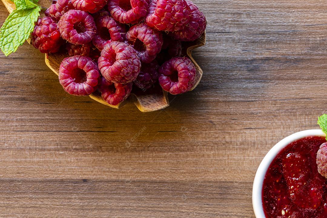 Fotos Colher com framboesa e tigela com geleia de framboesa em fundo de madeira,