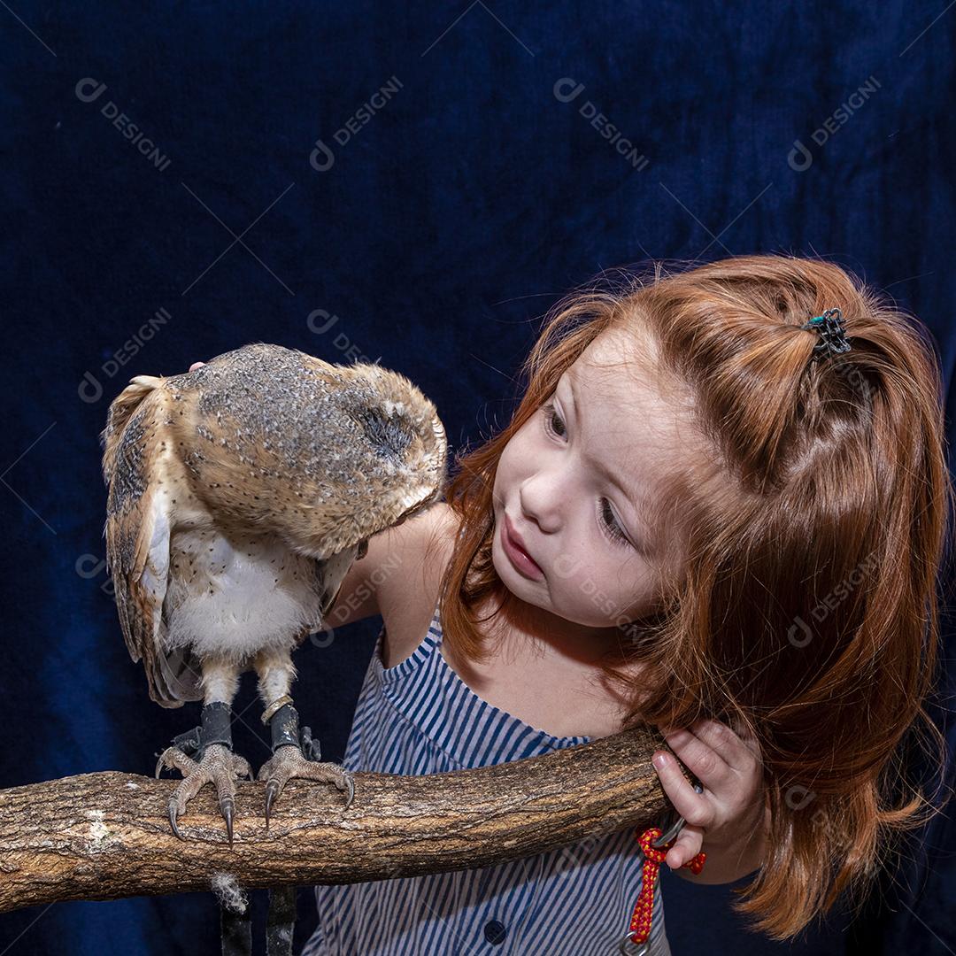 Linda garota ruiva tirando foto com sua coruja de estimação Imagem JPG