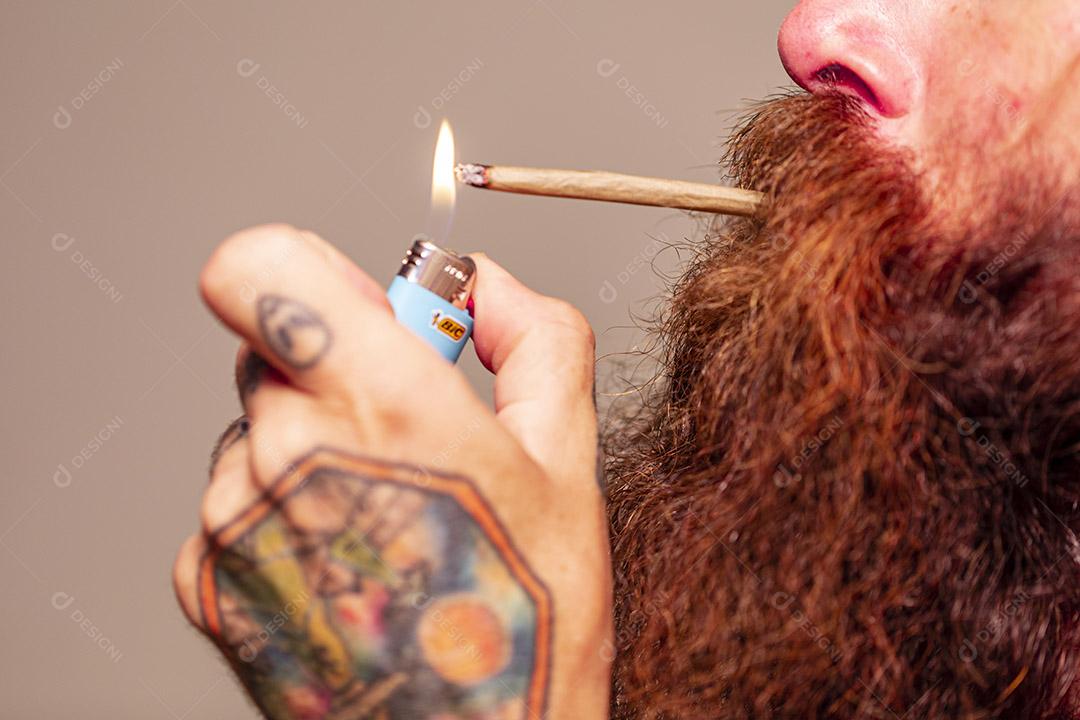 Homem com barba ruiva fumando um baseado cannabis Imagem JPG