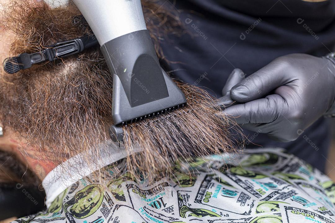 Homem secando a barba no barbeiro.Imagem JPG