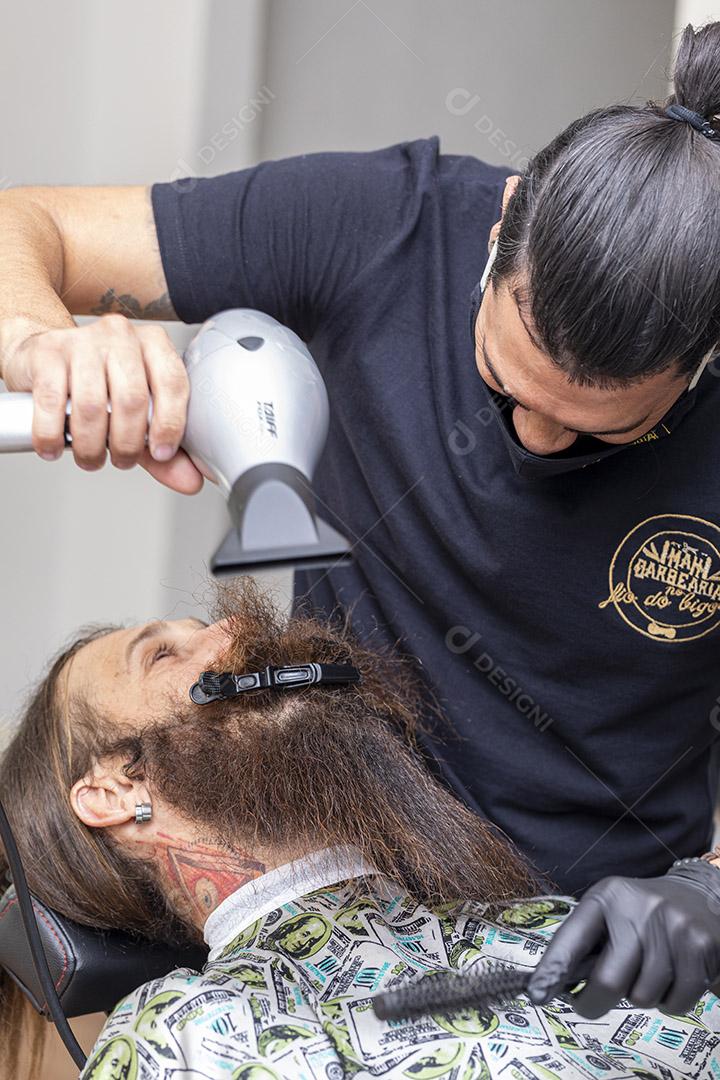 Homem secando a barba no barbeiro.Imagem JPG