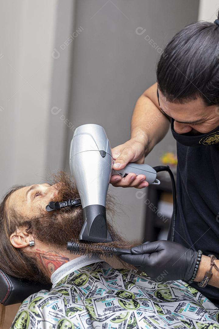 Homem secando a barba no barbeiro.Imagem JPG