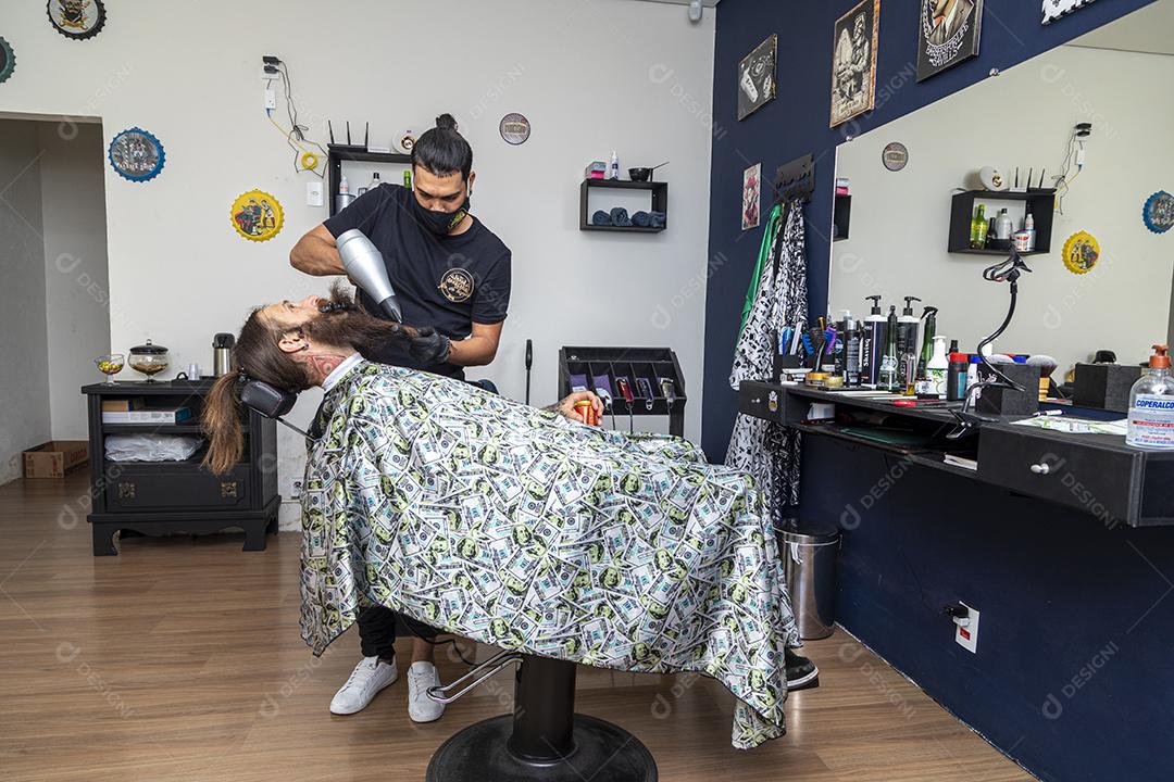 Homem secando a barba no barbeiro.Imagem JPG