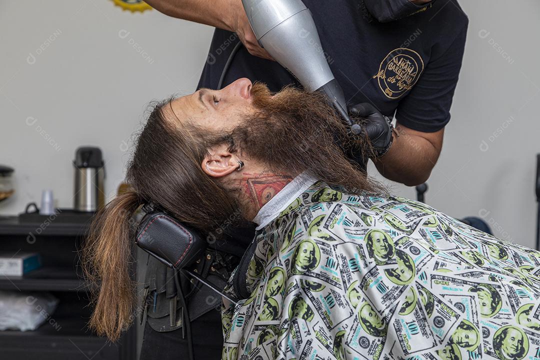 Homem secando a barba no barbeiro.Imagem JPG