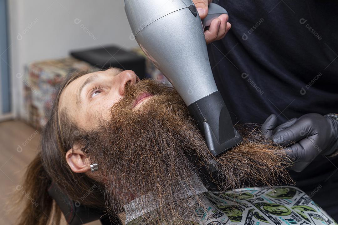 Homem secando a barba no barbeiro.Imagem JPG