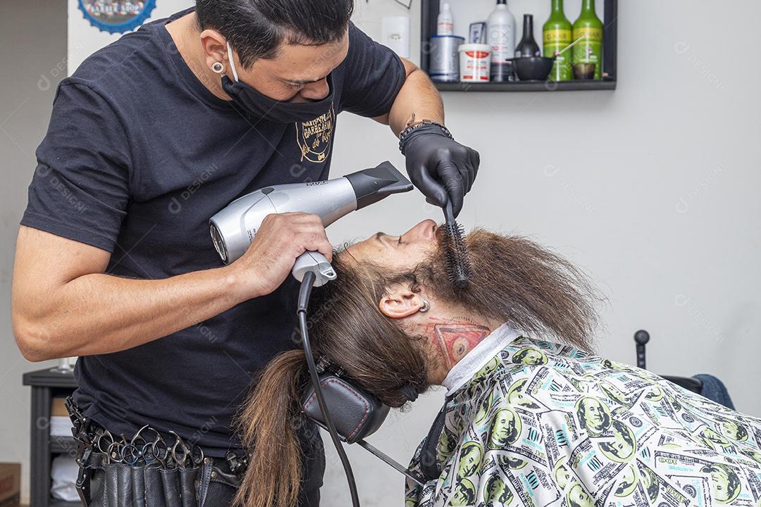 Homem secando a barba no barbeiro.Imagem JPG