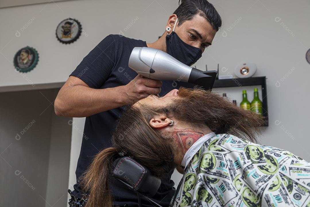 Homem secando a barba no barbeiro.Imagem JPG