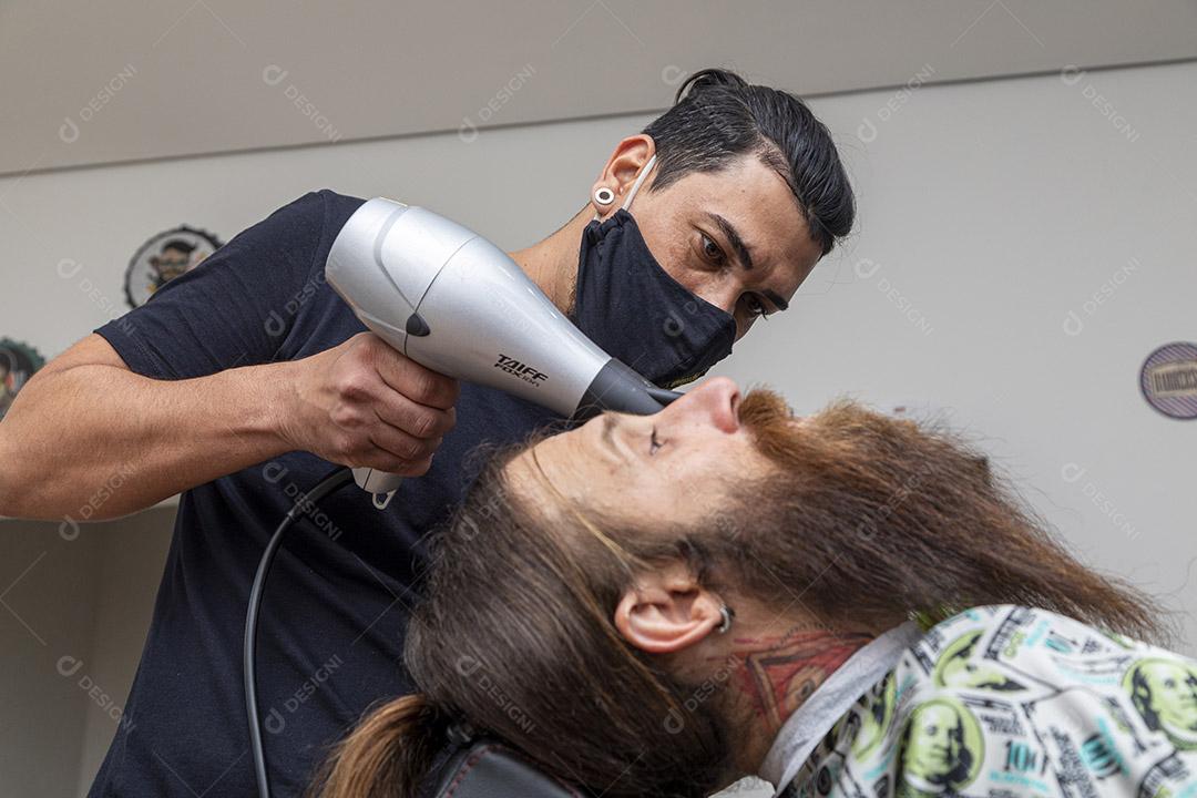 Homem secando a barba no barbeiro.Imagem JPG