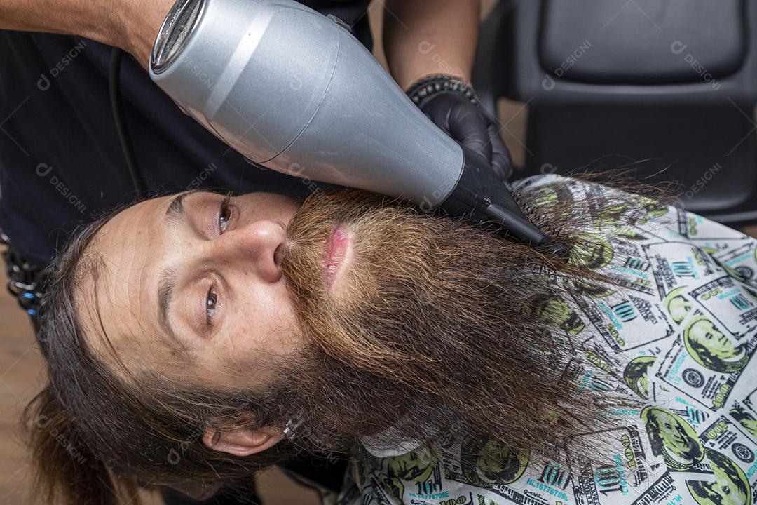 Homem secando a barba no barbeiro.Imagem JPG