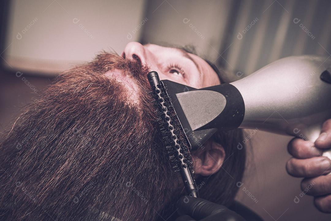 Homem secando a barba no barbeiro.Imagem JPG