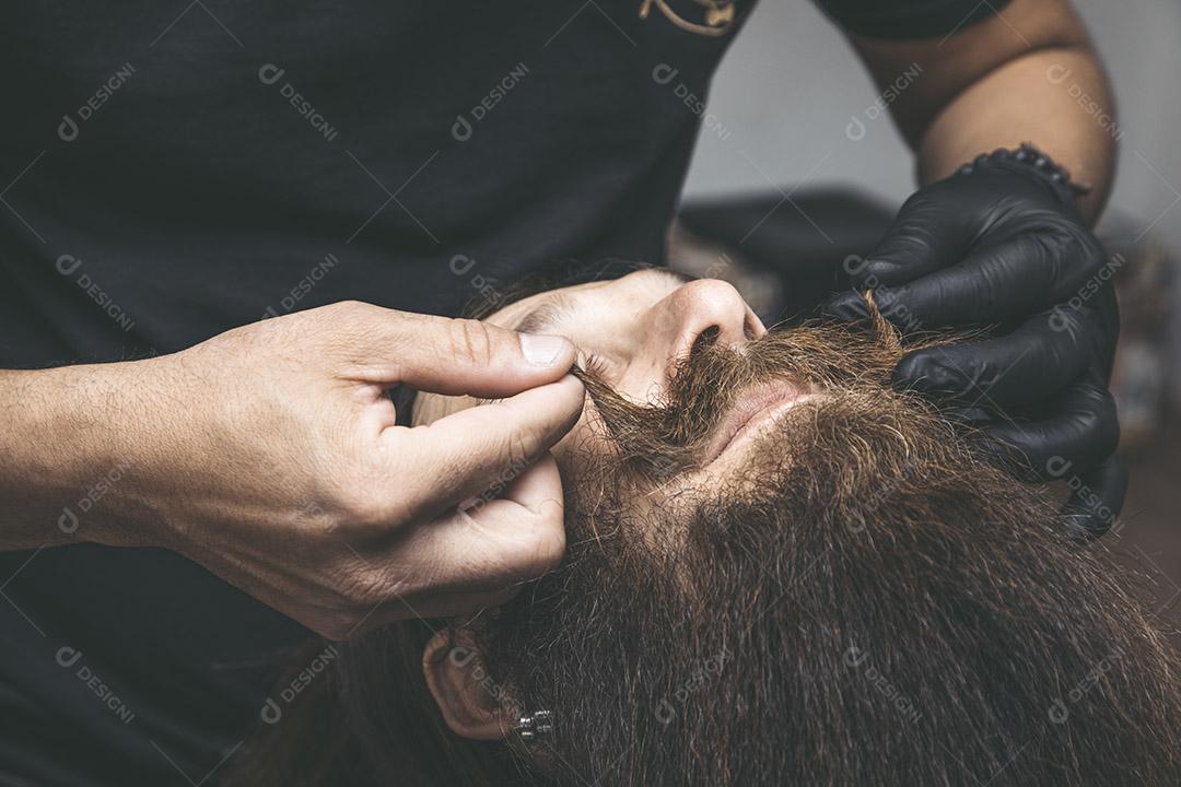 Barbeiro cortando o bigode de um homem.Imagem JPG