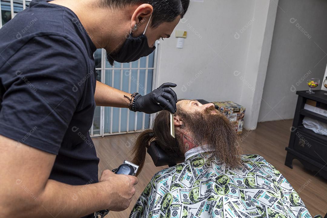 Barbeiro usando barbeador para cortar a barba de um homem. Imagem JPG