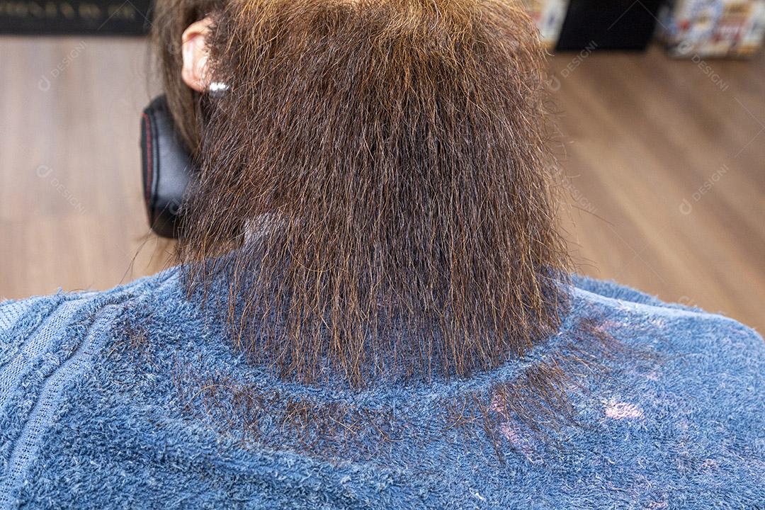 Barbeiro usando barbeador para cortar a barba de um homem Imagem JPG