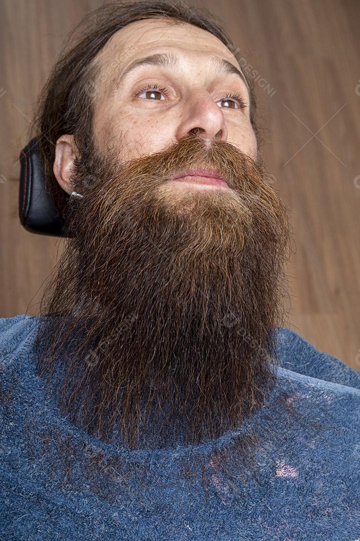 Barbeiro usando barbeador para cortar a barba de um homem Imagem JPG