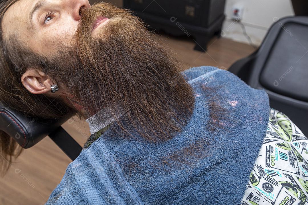 Homem ruivo sentado na cadeira de barbearia exibindo sua bela barba cortada Imagem JPG