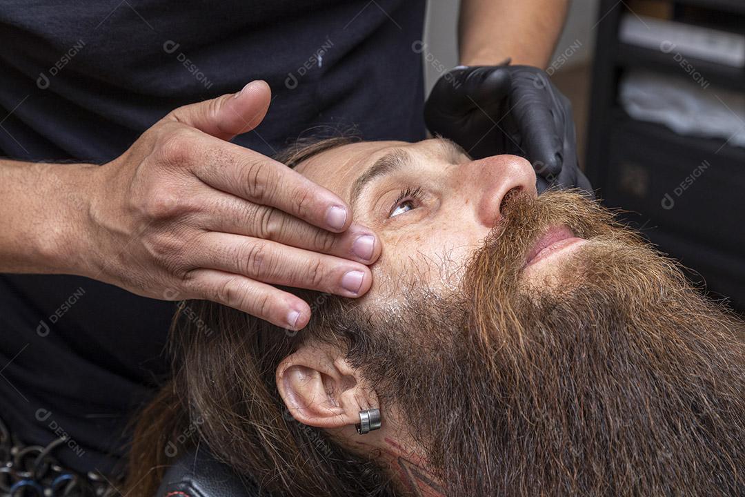 Barbeiro aplicando creme na barba do cliente Imagem JPG