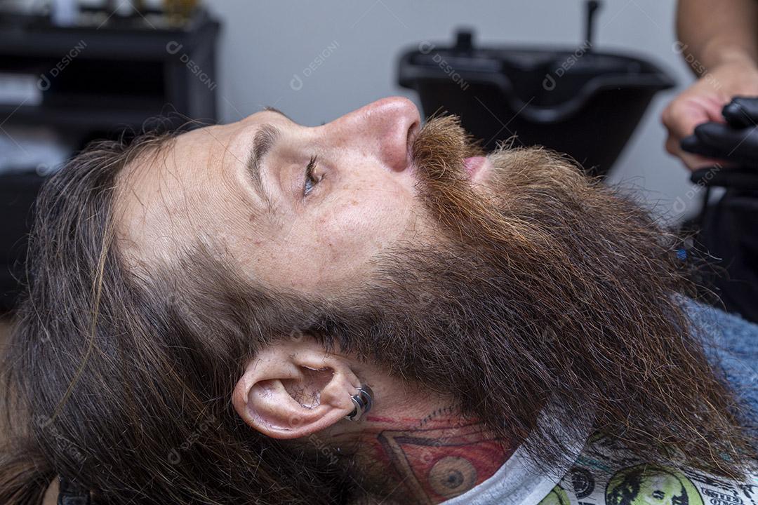 Homem ruivo sentado na cadeira de barbearia exibindo sua bela barba cortada Imagem JPG