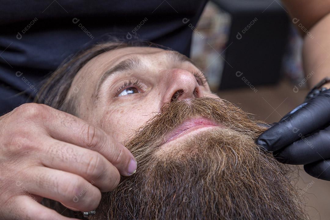 Barbeiro cortando o bigode de um homem.Imagem JPG