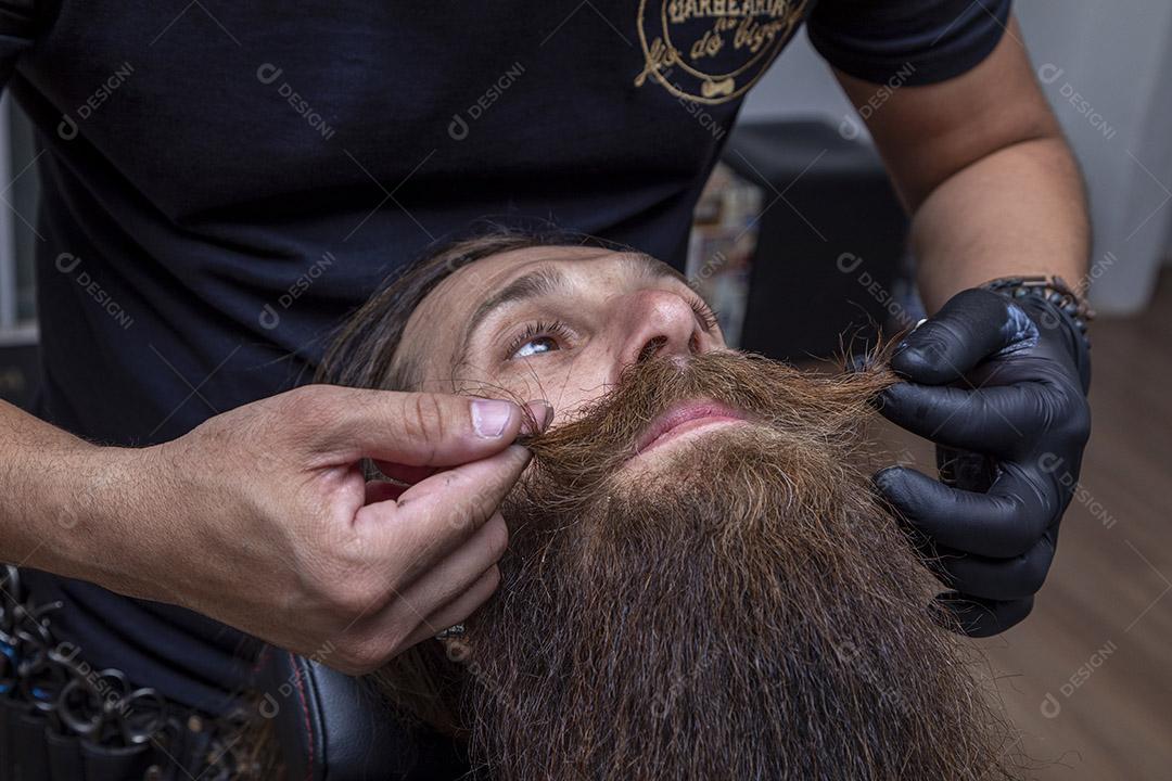 Barbeiro cortando o bigode de um homem.Imagem JPG