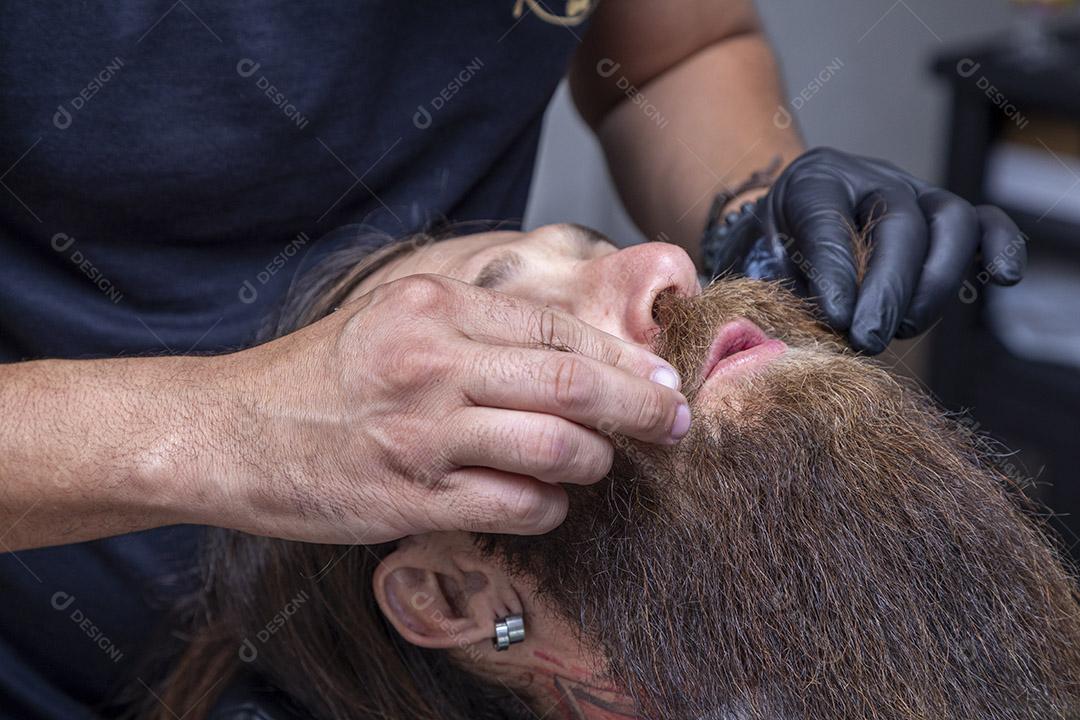 Barbeiro cortando o bigode de um homem.Imagem JPG