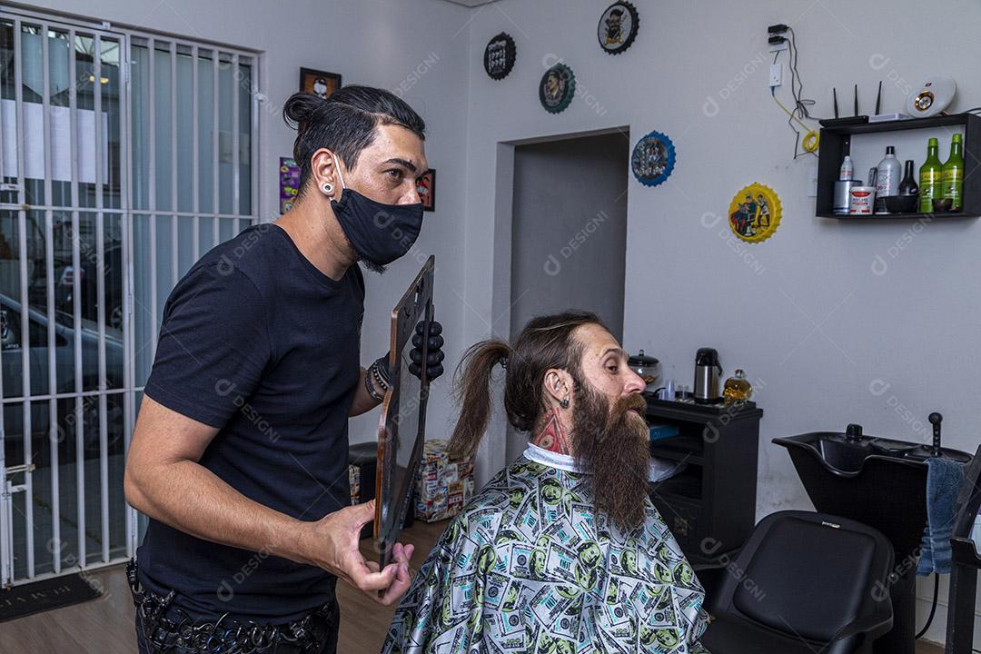 Barbeiro mostrando ao cliente a barba acabada.Imagem JPG