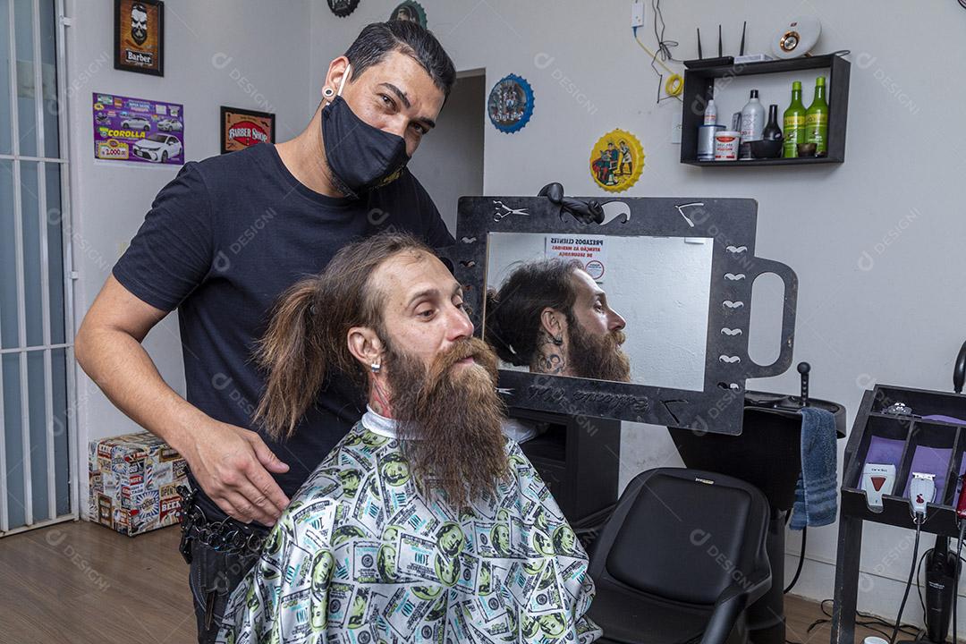 Barbeiro mostrando ao cliente a barba acabada.Imagem JPG