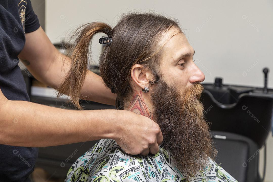 Barbeiro aplicando creme na barba do cliente.Imagem JPG