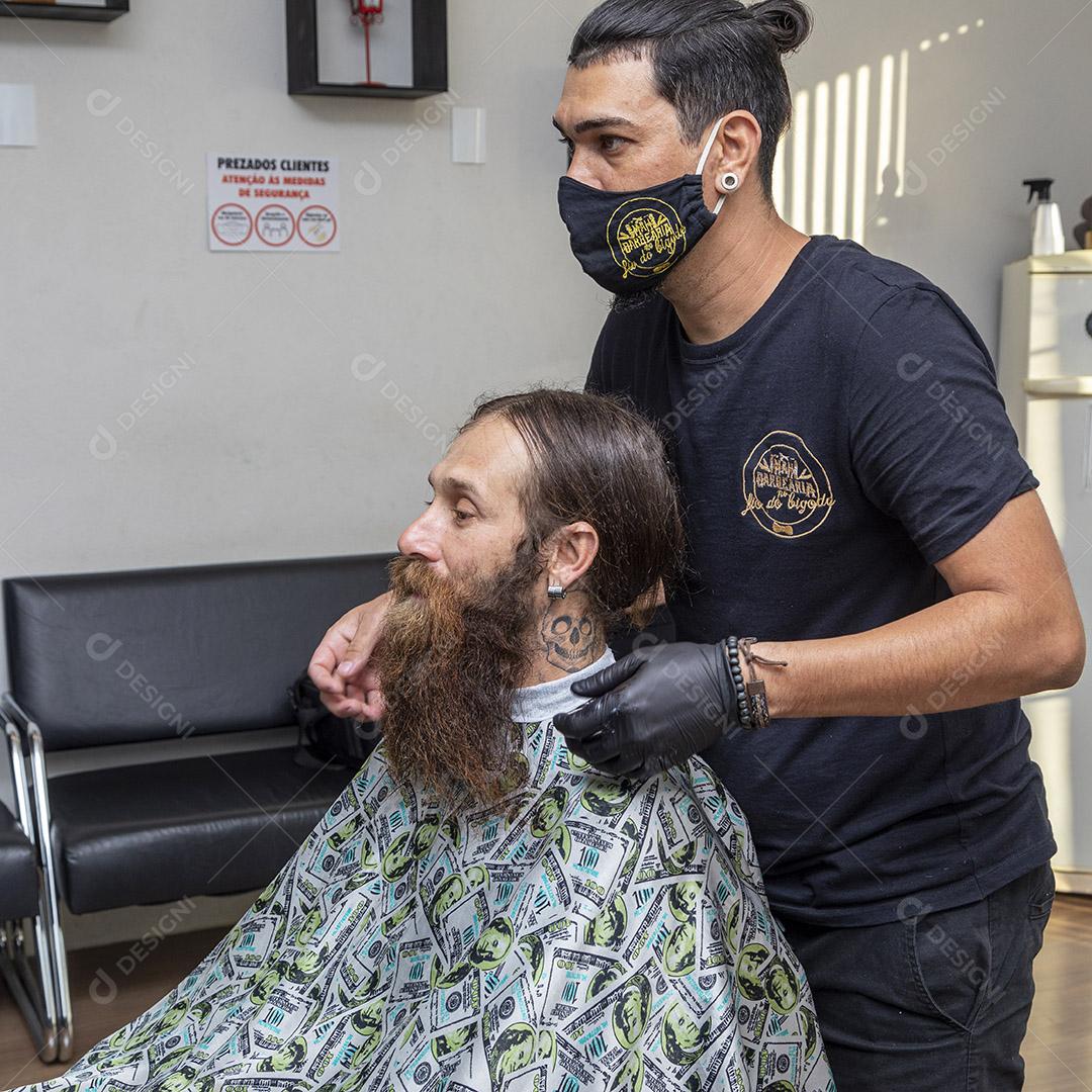 Fotos barbeiro aplicando creme na barba do cliente.