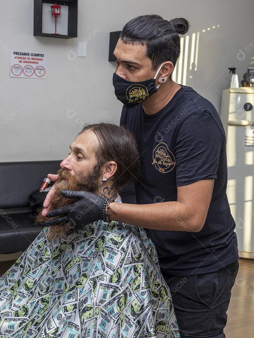 Fotos barbeiro aplicando creme na barba do cliente.