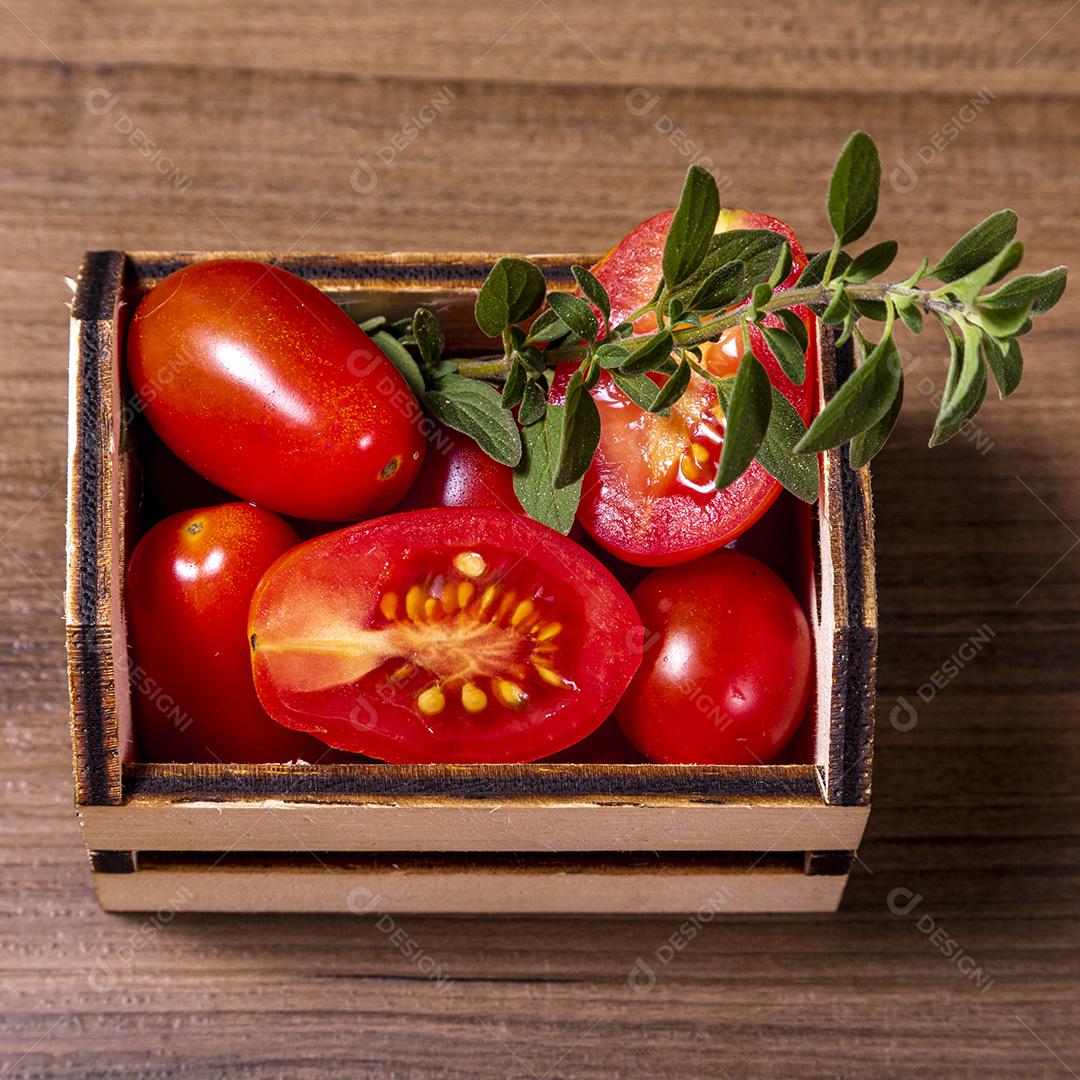 caixa de madeira com tomate e galho de orégano.Imagem JPG