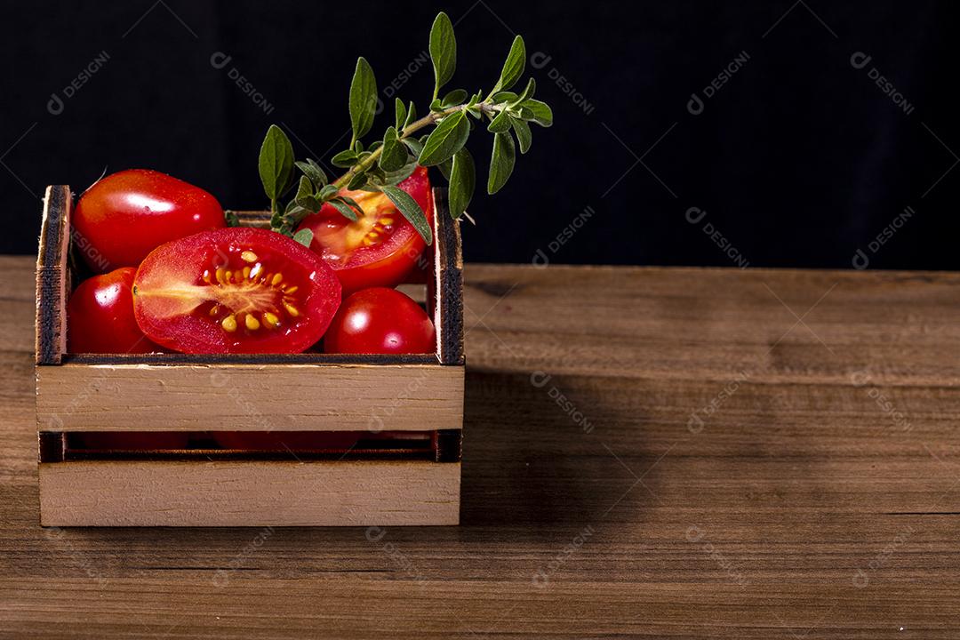 Caixa de madeira com tomate e galho de orégano.Imagem JPG