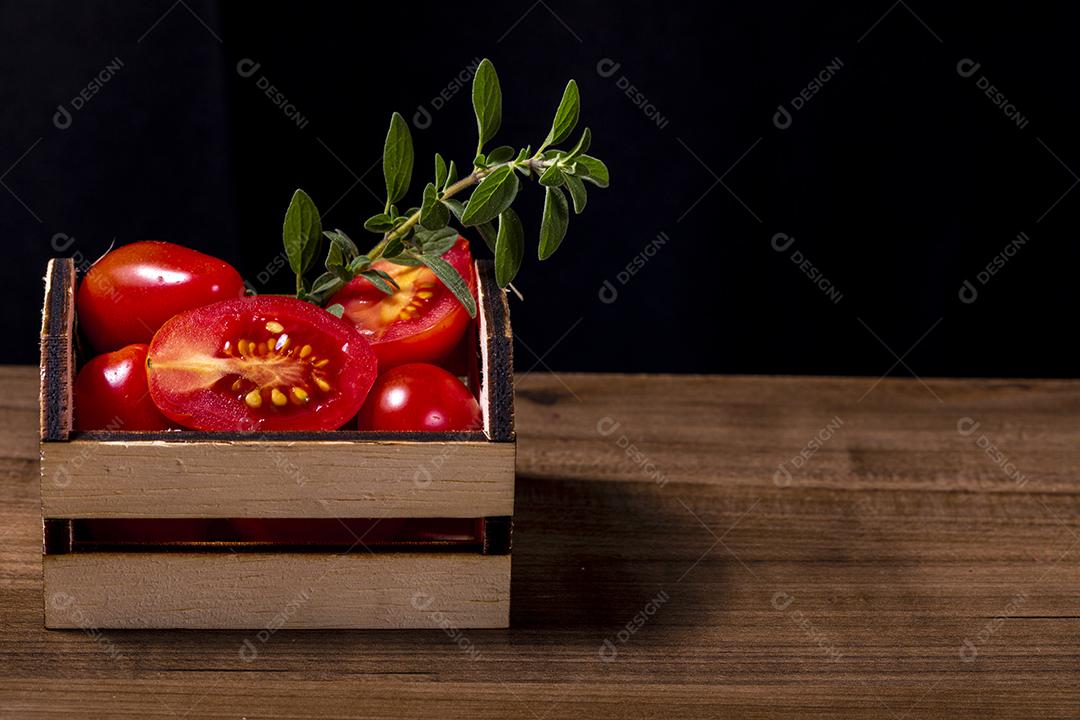 Caixa de madeira com tomate e galho de orégano.Imagem JPG