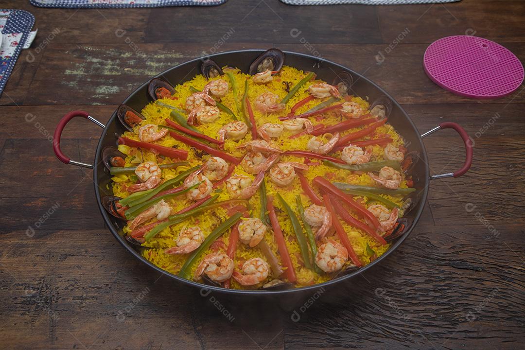 Paelha de frutos do mar tradicional na frigideira em uma mesa de madeira velha Imagem JPG