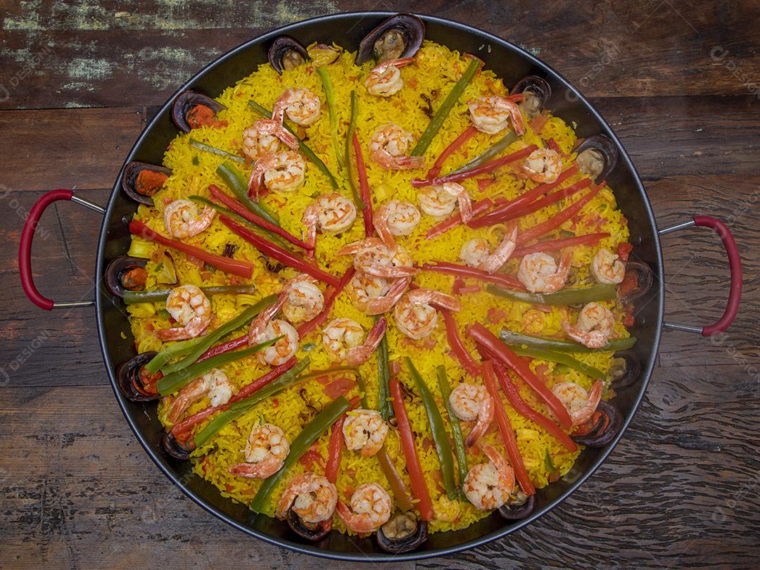 Paelha de frutos do mar tradicional na frigideira em uma mesa de madeira velha Imagem JPG