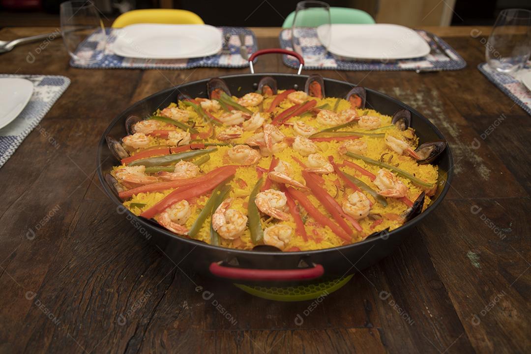 Paelha de frutos do mar tradicional na frigideira em uma mesa de madeira velha Imagem JPG
