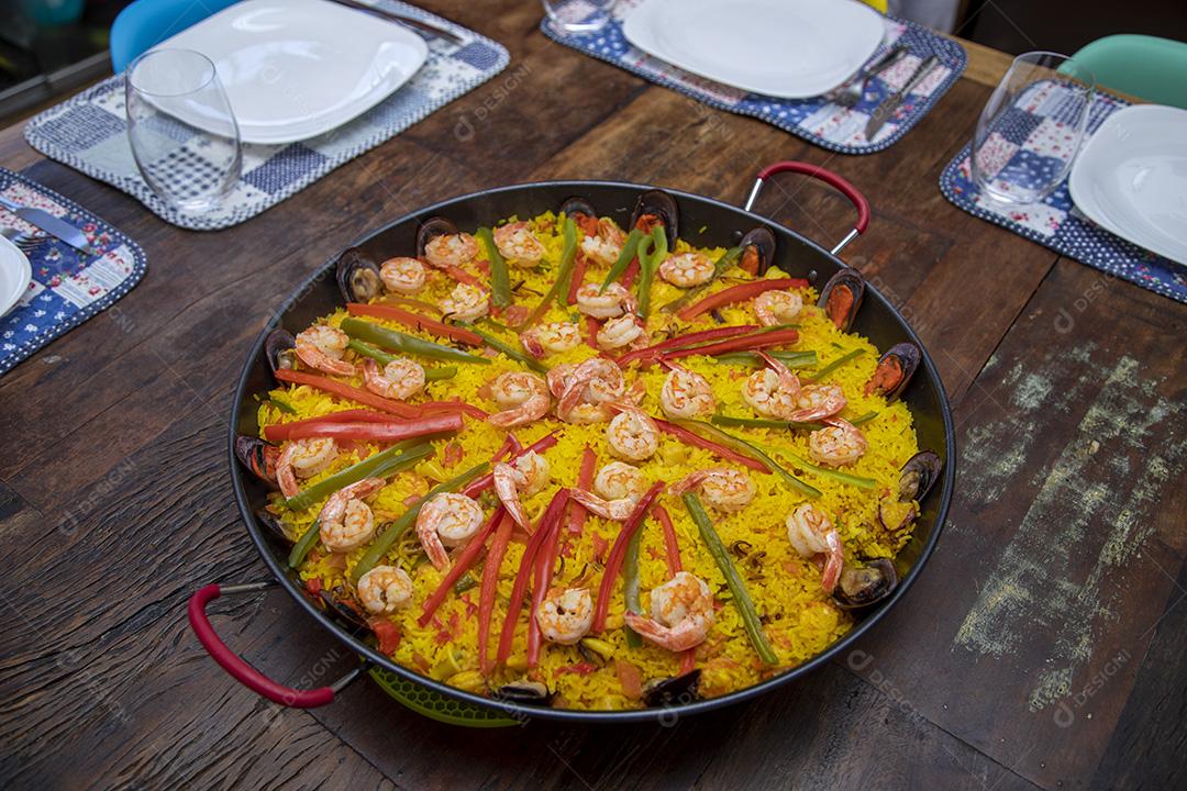 Paelha de frutos do mar tradicional na frigideira em uma mesa de madeira velha Imagem JPG