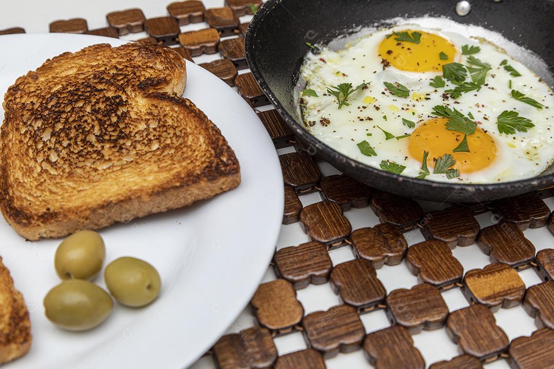 Ovos fritos com salsa em uma panela de ferro rústica, torradas Imagem JPG