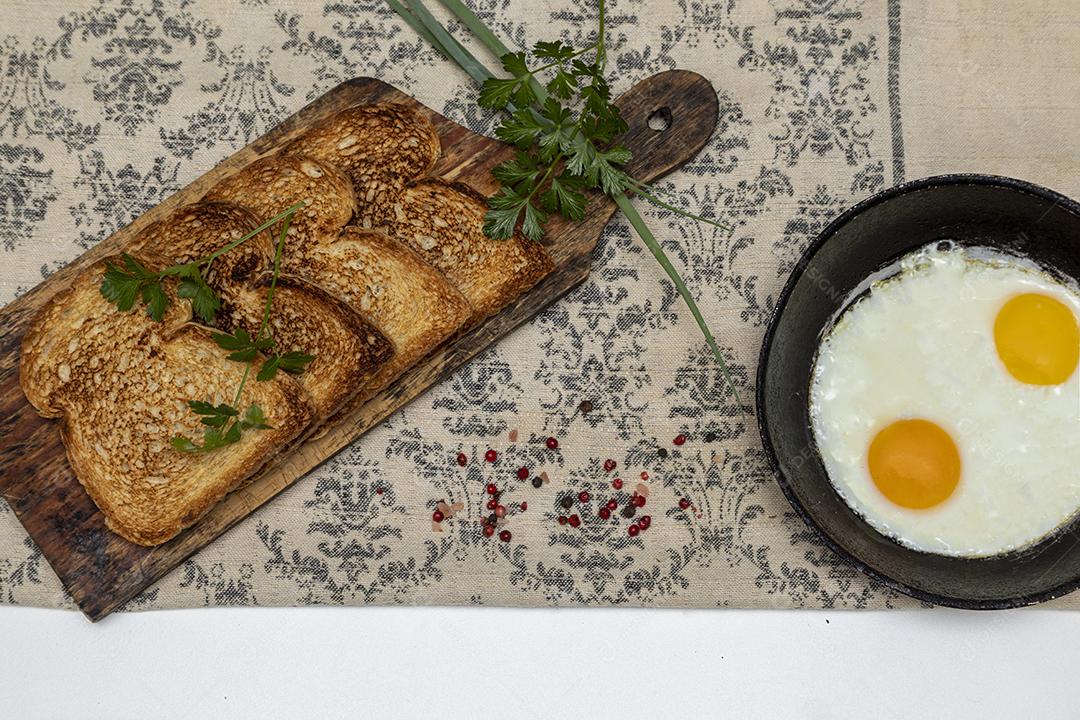 Ovos fritos com salsa em uma panela de ferro rústica, torradas Imagem JPG