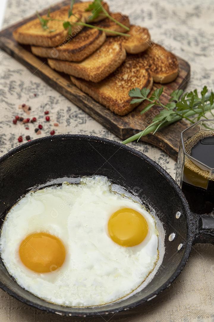 Ovos fritos com salsa em uma panela de ferro rústica, torradas Imagem JPG