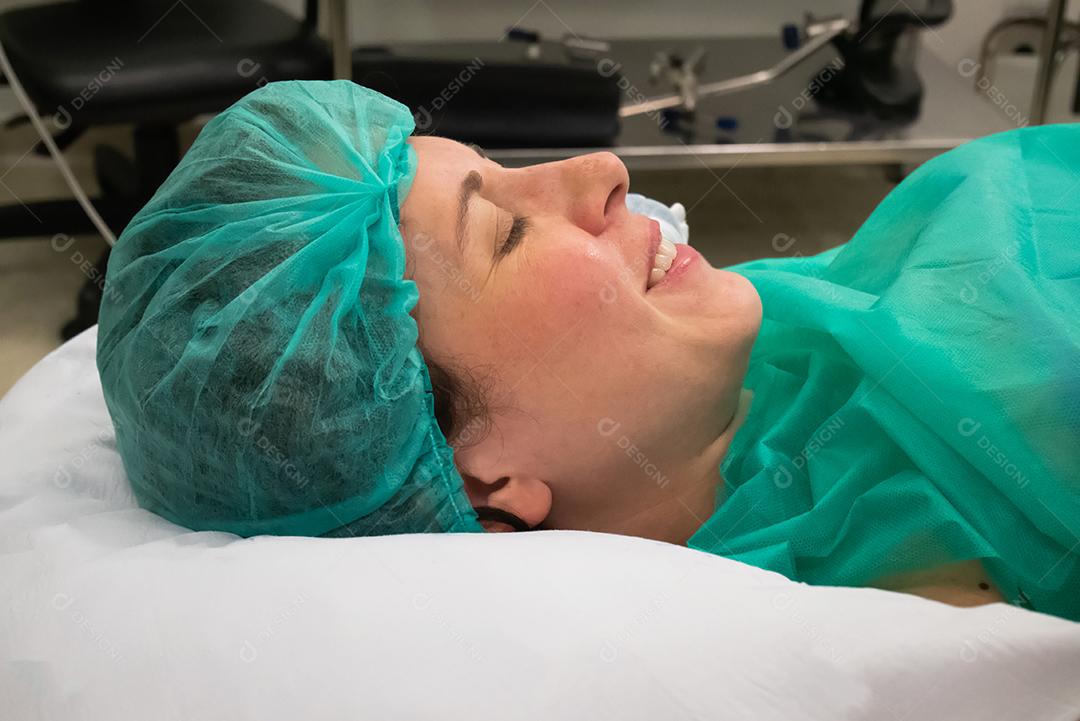 Mulher sorrindo esperando para ter seu bebê na cama do Hospital
