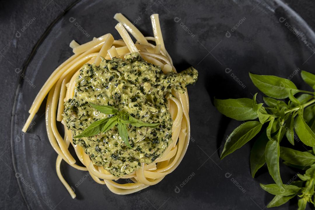 Macarrão Esparguete com molho pesto e folhas de manjericão fresco Imagem JPG