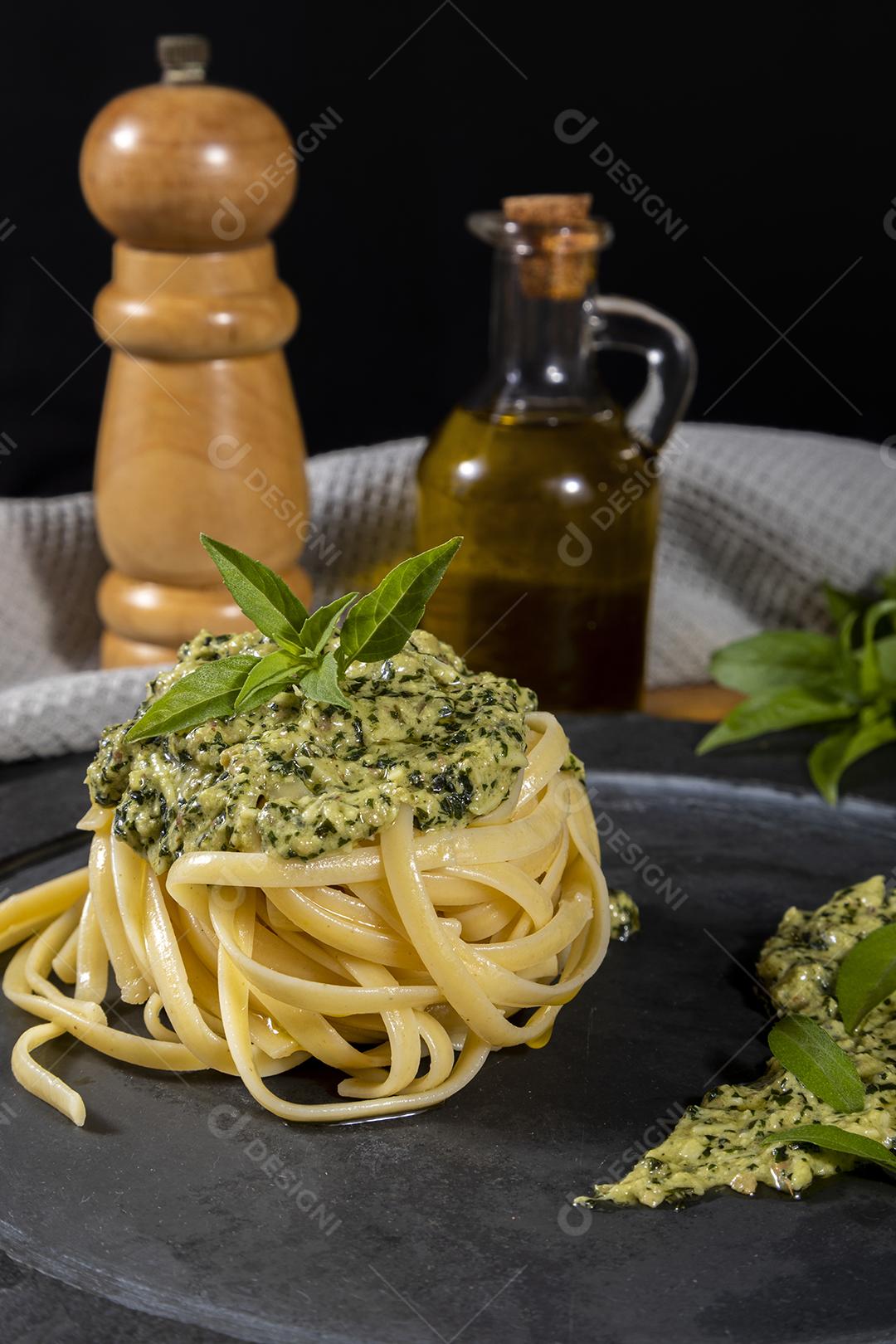 Esparguete de macarrão com molho pesto e folhas de manjericão fresco Imagem JPG