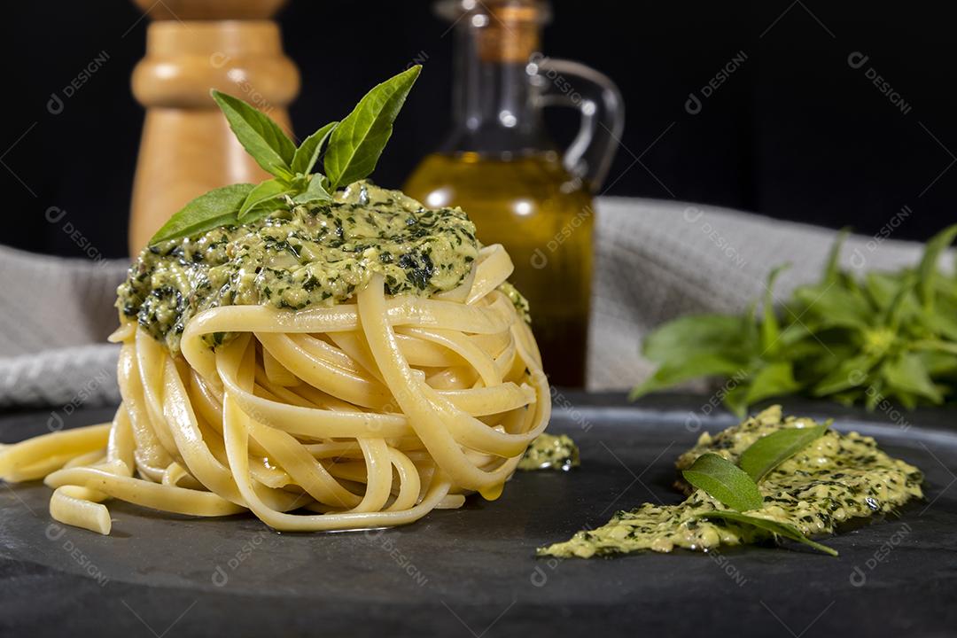 Esparguete de macarrão com molho pesto e folhas de manjericão fresco Imagem JPG