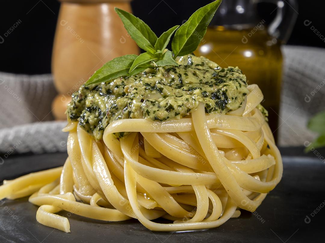 Esparguete de macarrão com molho pesto e folhas de manjericão fresco Imagem JPG