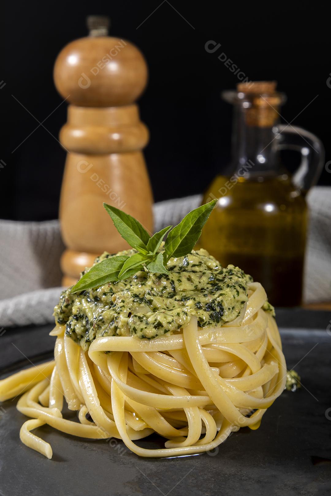 Esparguete de macarrão com molho pesto e folhas de manjericão fresco Imagem JPG