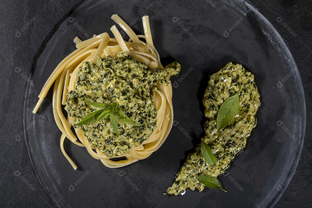 Esparguete de macarrão com molho pesto e folhas de manjericão fresco Imagem JPG