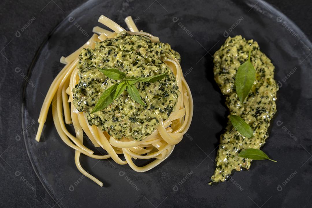 Esparguete de macarrão com molho pesto e folhas de manjericão fresco Imagem JPG
