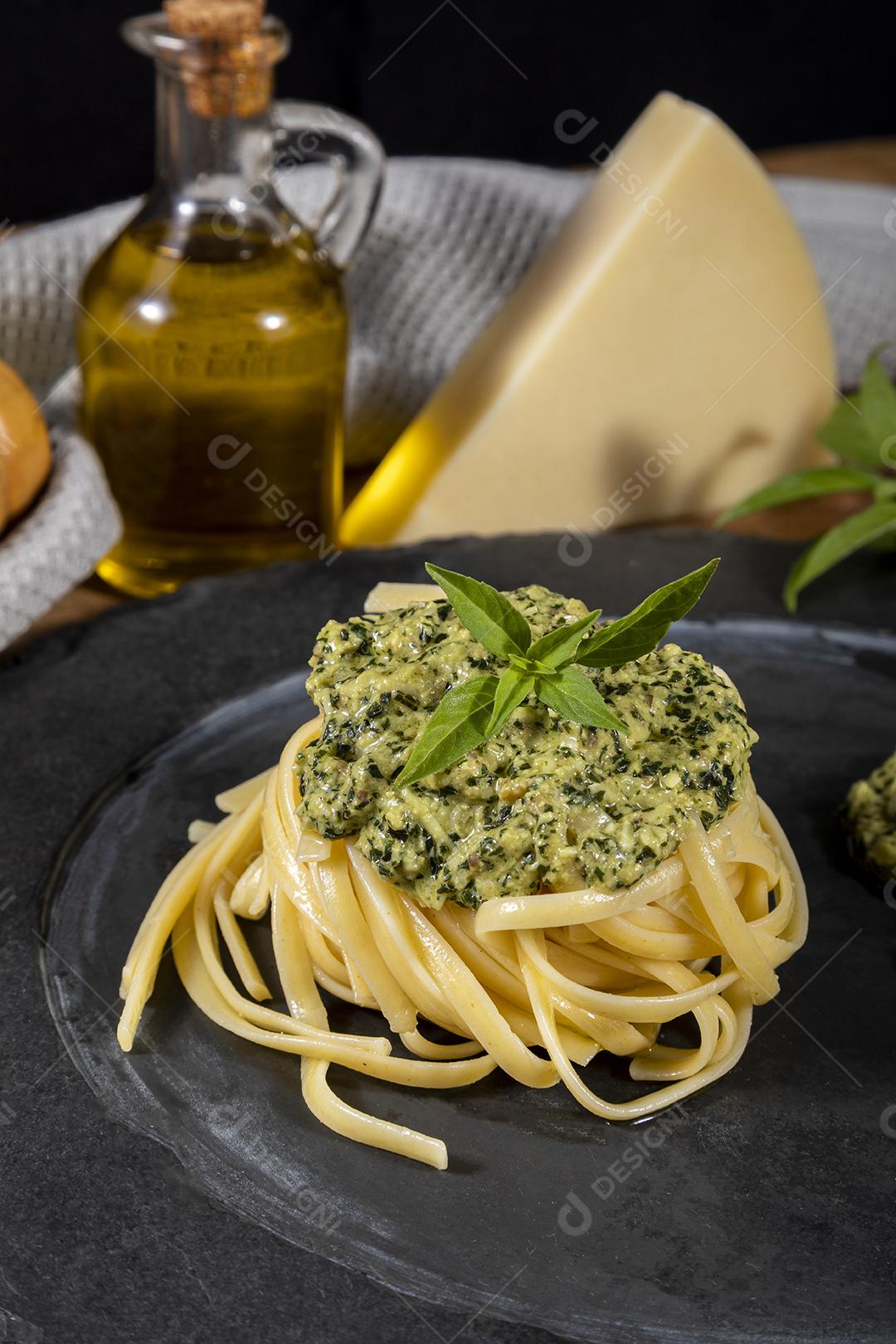 Esparguete de macarrão com molho pesto e folhas de manjericão fresco Imagem JPG