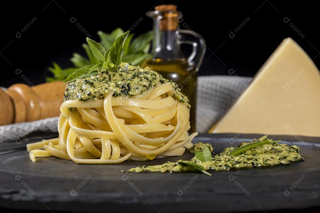 Esparguete de macarrão com molho pesto e folhas de manjericão fresco Imagem JPG