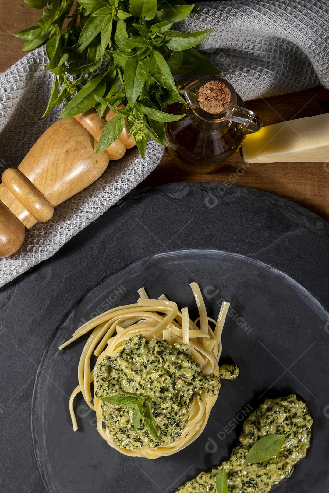 Esparguete de macarrão com molho pesto e folhas de manjericão fresco Imagem JPG